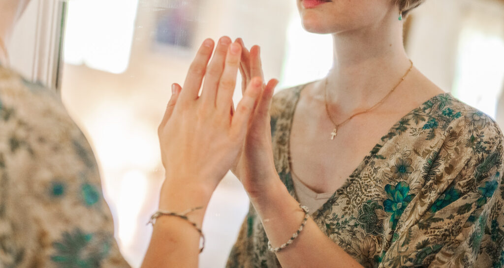 Frau berührt Spiegel mit ihrer Hand, Reflexion im Inner Work.
